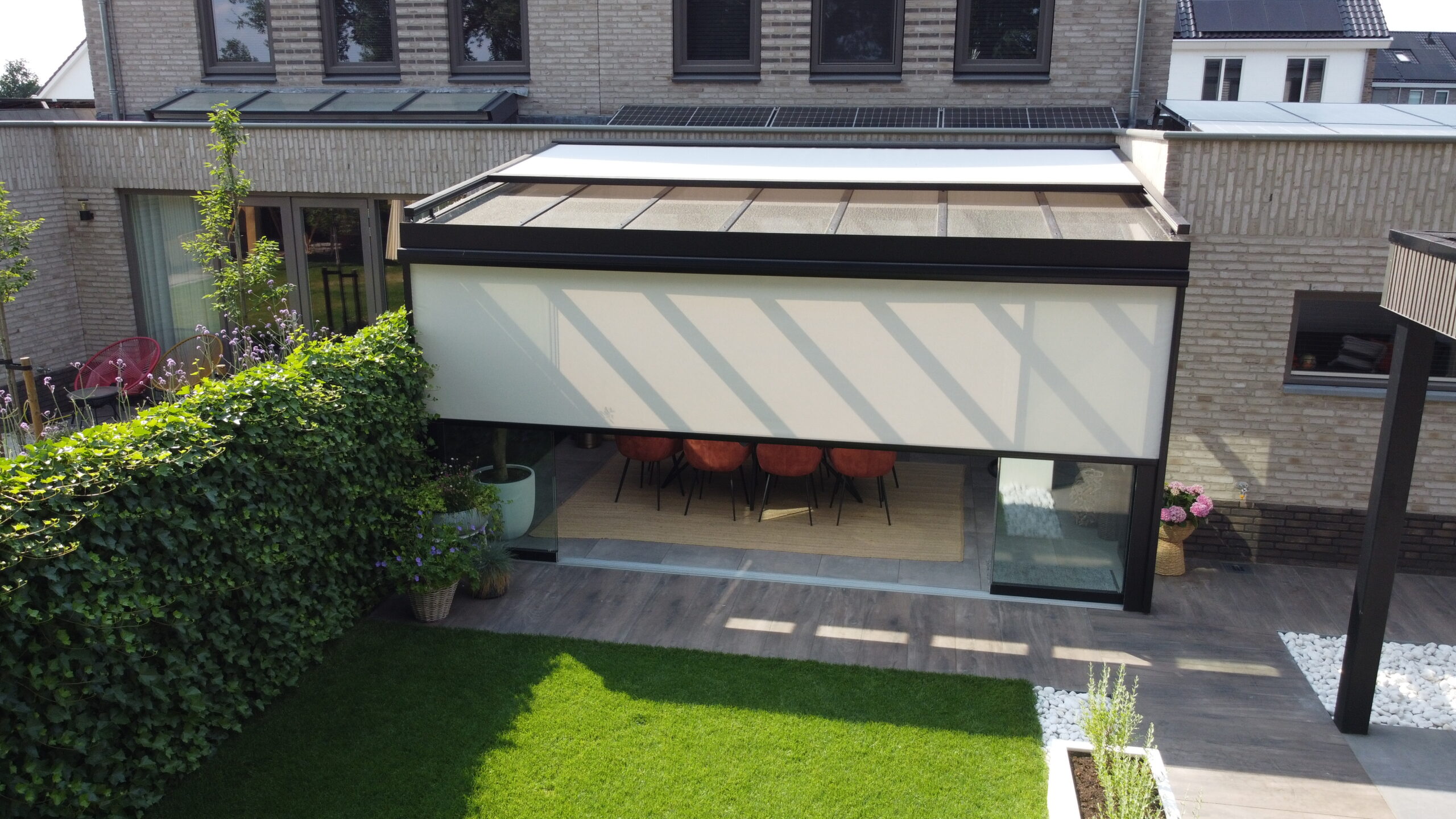 Veranda met zonwering en screens, met gebruik van zonwerindoeken van Serge Ferrari en Somfy motoren voor de afstandsbediening {{brizy_dc_image_alt imageSrc=